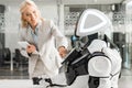 Businesswoman operating robot while holding digital