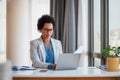 Businesswoman with papers working on laptop while sitting at office desk Royalty Free Stock Photo