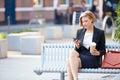 Businesswoman On Park Bench With Coffee Using Mobile Phone