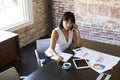 Businesswoman On Phone Making Notes On Document In Boardroom