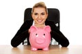 Businesswoman with a piggybank behind the desk