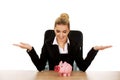 Businesswoman with a piggybank behind the desk