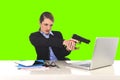 Businesswoman pointing gun to computer laptop sitting at office green chroma key Royalty Free Stock Photo