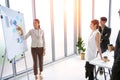 Businesswoman pointing towards graph and giving presentation explaining the idea to her business colleagues in the office. Group Royalty Free Stock Photo