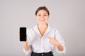 The businesswoman points her finger at an empty mobile phone screen for a copy space for advertising on a gray background Royalty Free Stock Photo