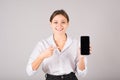 The businesswoman points her finger at an empty mobile phone screen for a copy space for advertising on a gray background Royalty Free Stock Photo