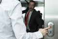 Businesswoman pressing elevator up button. Businessman confused trying to stop the elevator. Royalty Free Stock Photo