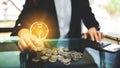 Businesswoman putting a light bulb over coins stack on the table while calculating Royalty Free Stock Photo