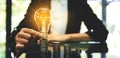 Businesswoman putting lightbulb over coins stack on table Royalty Free Stock Photo