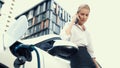 Businesswoman recharge her electric car from charging station. Peruse