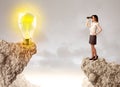 Businesswoman on rock mountain with idea bulb