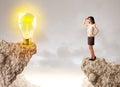 Businesswoman on rock mountain with idea bulb