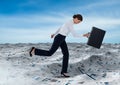 Businesswoman running with briefcase in sea of documents under blue sky clouds Royalty Free Stock Photo