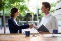 Businesswoman shaking hands with businessman at counter