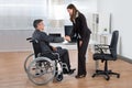 Businesswoman Shaking Hands With Businessman On Wheelchair