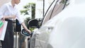 Businesswoman with shopping bag recharge her EV car. Peruse