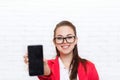 Businesswoman show cell smart phone screen with empty copy space wear red jacket glasses happy smile Royalty Free Stock Photo
