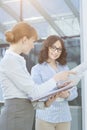 Businesswoman showing document to colleague in office Royalty Free Stock Photo