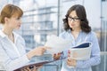 Businesswoman showing document to female colleague in office Royalty Free Stock Photo