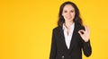 Businesswoman showing ok gesture yellow background Royalty Free Stock Photo