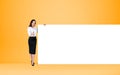 Businesswoman shows thumb up near mockup poster on bright background Royalty Free Stock Photo