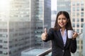 Businesswoman shows the thumbs up in front of modern office buildings in the city