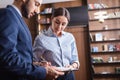 Businesswoman signing paper on clipboard near arabian businessman on blurred foreground. Royalty Free Stock Photo