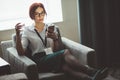 Businesswoman sits in armchair with water glass in hand and talking on phone Royalty Free Stock Photo