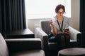 Businesswoman sits in armchair with water glass in hand and talking on phone Royalty Free Stock Photo