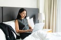 Businesswoman sitting on bed in hotel room while working on computer. Business trip, work from home concept Royalty Free Stock Photo