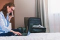 Businesswoman working in hotel room, using laptop and mobile phone Royalty Free Stock Photo