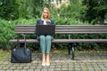 businesswoman sitting on the bench in the city park and working on laptop. outdoor office freelance work