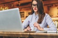 Businesswoman sitting in cafe at table in front of laptop,drinking coffee. Girl blogging,learning online,checking email.