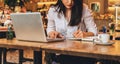 Businesswoman is sitting in cafe at table in front of laptop, making notes in notebook, working.Student learning online. Royalty Free Stock Photo