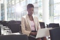Businesswoman sitting on chair and using laptop in lobby Royalty Free Stock Photo