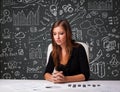 Businesswoman sitting at desk with business scheme and icons