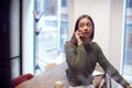 Businesswoman Sitting On Desk In Meeting Room Talking On Mobile Phone Royalty Free Stock Photo