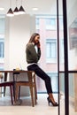 Businesswoman Sitting On Desk In Meeting Room Talking On Mobile Phone Royalty Free Stock Photo