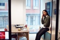 Businesswoman Sitting On Desk In Meeting Room Talking On Mobile Phone Royalty Free Stock Photo