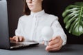 Businesswoman sitting at desk near pc on grey background, close up hand hold white light bulb, ideas of new ideas Royalty Free Stock Photo