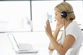 Businesswoman Sitting At Desk In Office Using Laptop Wearing Headset