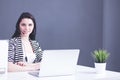 Businesswoman sitting at desk in office using laptop wearing headset