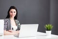 Businesswoman sitting at desk in office using laptop wearing headset Royalty Free Stock Photo