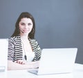 Businesswoman sitting at desk in office using laptop wearing headset