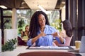 Businesswoman Sitting At Desk Taking Photo Of Proofs Or Design Layouts On Mobile Phone