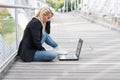 Businesswoman sitting on the floor of the street using a laptop Royalty Free Stock Photo