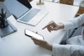 Businesswoman sitting in front of laptop computer at office desk and using mobile phone. Royalty Free Stock Photo