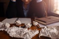 Businesswoman sitting with head in hands at desk and crumpled papers Royalty Free Stock Photo