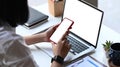 Businesswoman sitting at her workspace and using mock up mobile phone with blank screen. Royalty Free Stock Photo