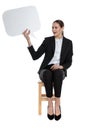 Businesswoman sitting and holding speech bubble and looking aside fascinated